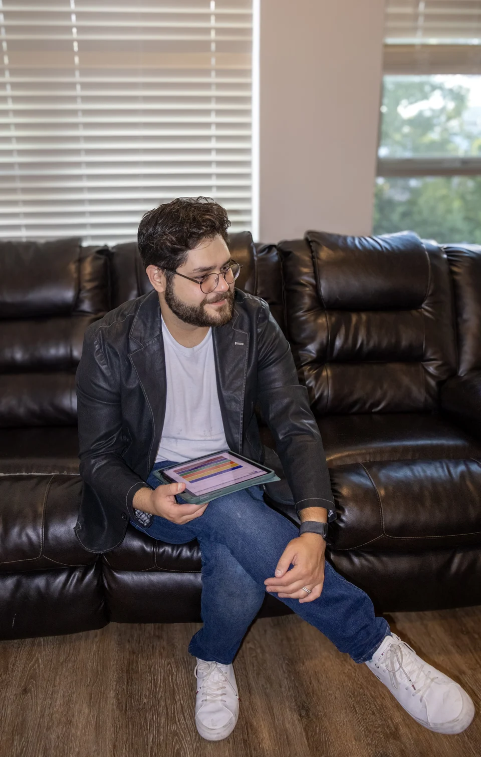 Patrick Domiciano seated on a sofa, holding a tablet.